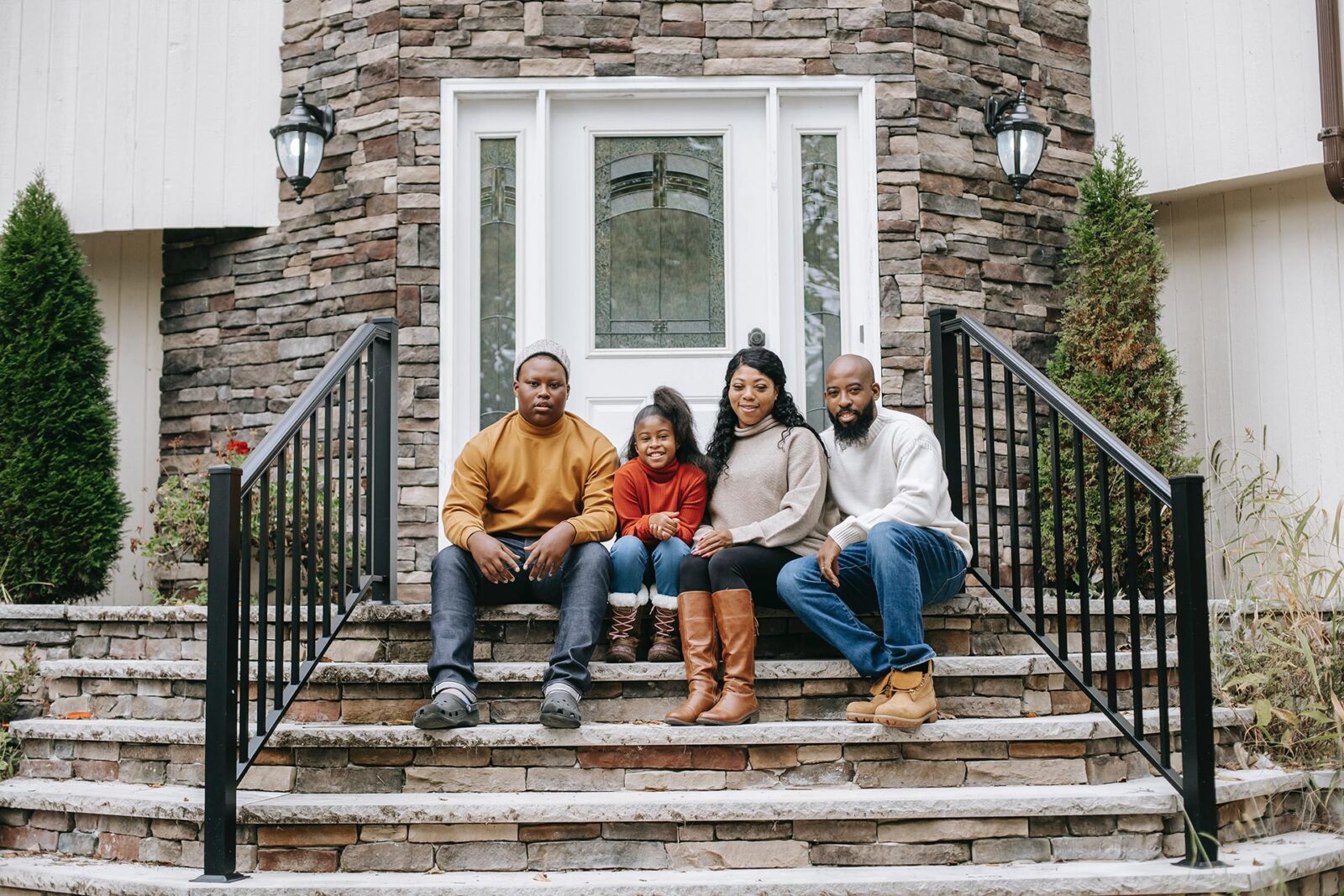 Family sitting together in front of house